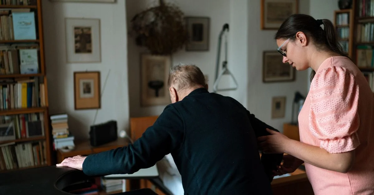 Un jeune soignant aide un homme âgé dans un salon élégant de Prague.