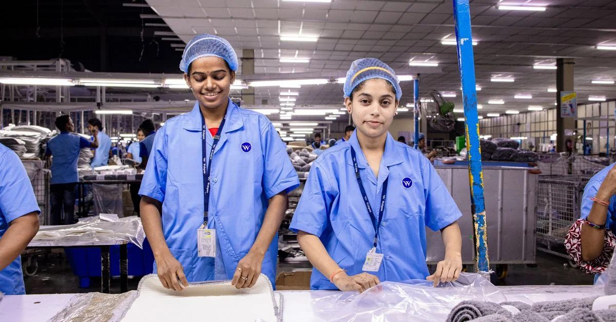 Des ouvrières en uniforme assemblent des tissus dans une usine textile moderne.