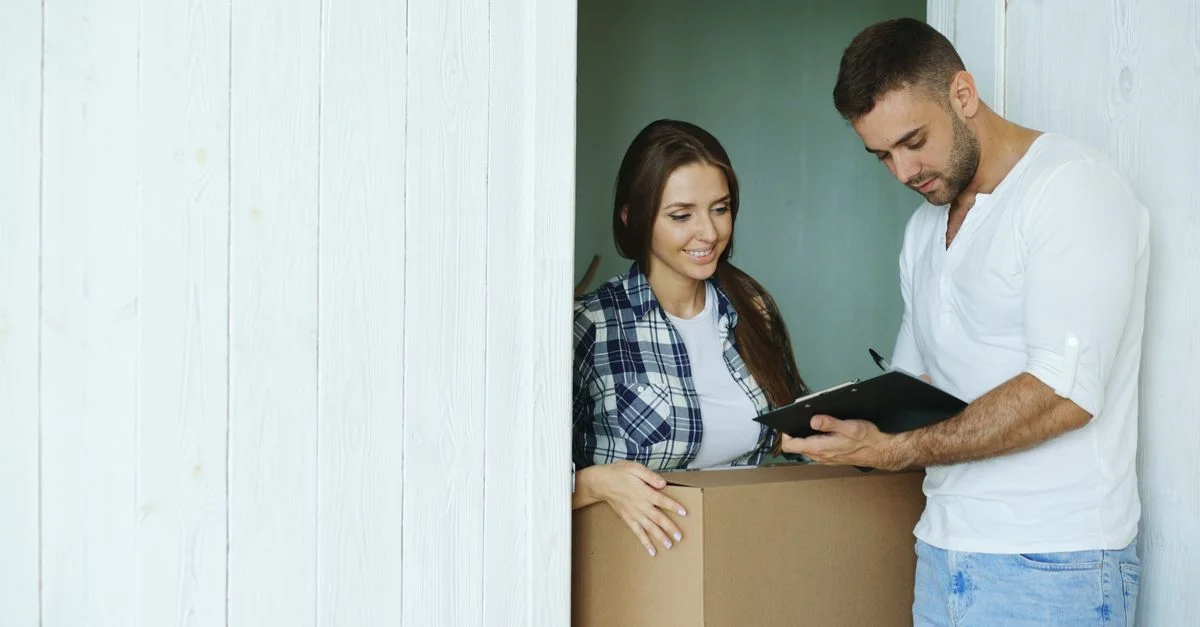 Jeune couple signant un document lors de leur emménagement dans leur nouvelle maison.