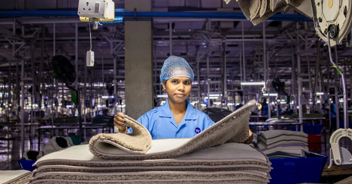 Une ouvrière arrange des tissus dans l'intérieur très fréquenté d'une usine textile.