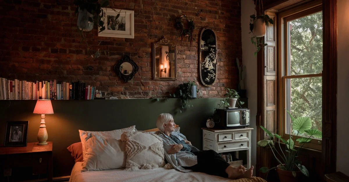 Une femme senior se relaxant dans une chambre confortable avec une décoration vintage et de la lumière naturelle.